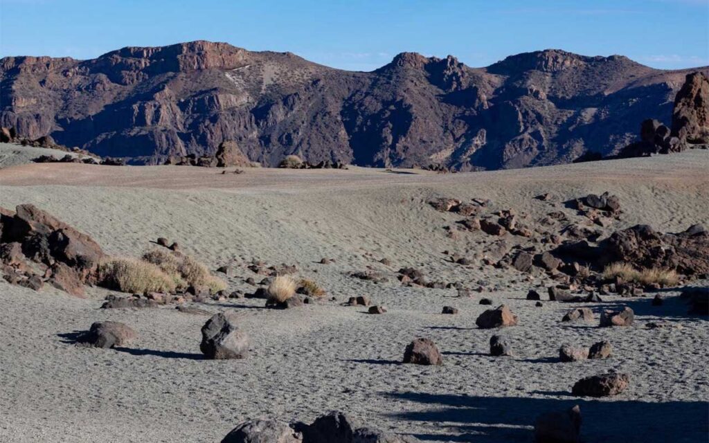 Paisaje árido en Canarias con terrenos secos, montañas erosionadas y vegetación escasa, reflejando el aumento de la aridez en la región
